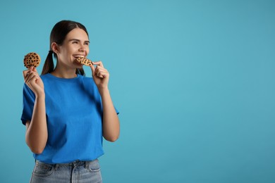 Photo of Young woman with chocolate chip cookies on light blue background, space for text