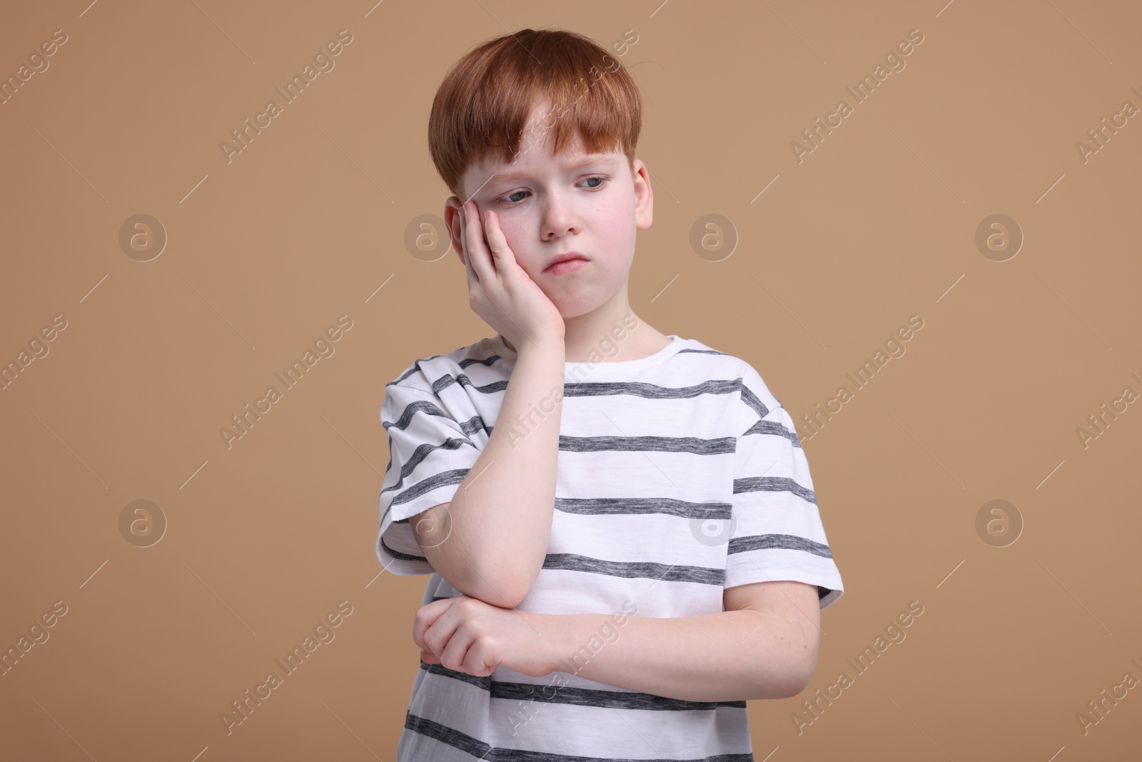 Photo of Portrait of sad little boy on beige background