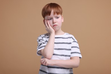 Portrait of sad little boy on beige background