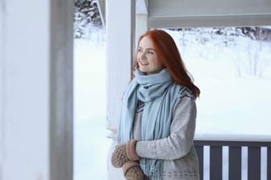 Photo of Beautiful young woman in wooden gazebo on snowy day outdoors. Winter vacation