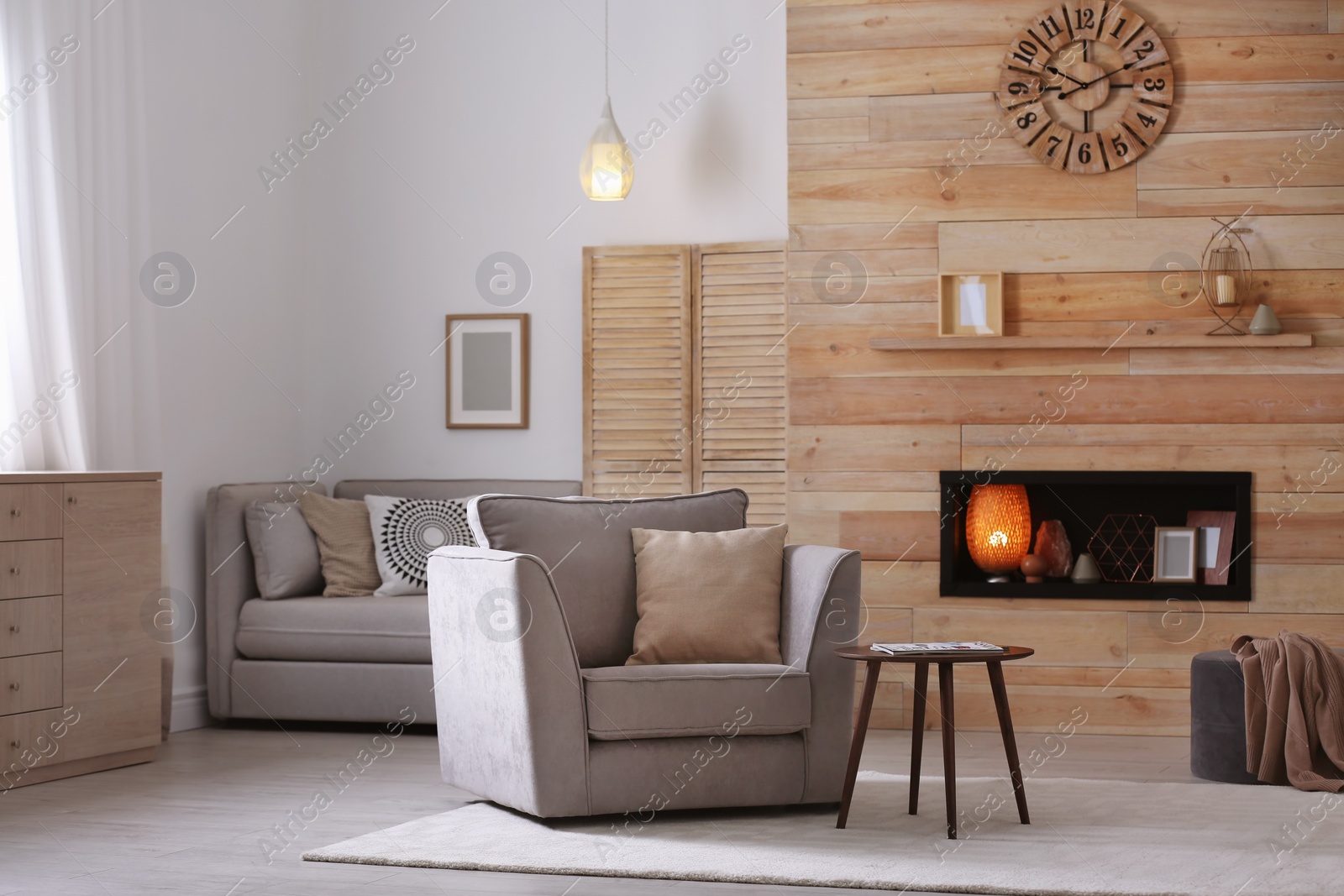 Photo of Cozy furnished apartment with niche in wooden wall and armchair. Interior design