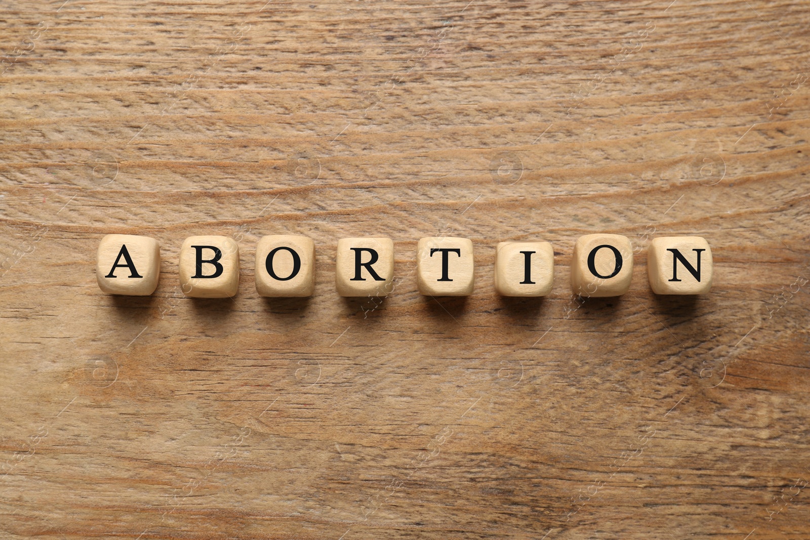 Photo of Word Abortion made of cubes on wooden background, flat lay