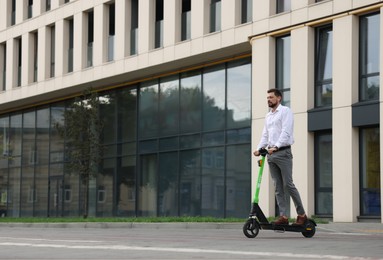 Photo of Businessman riding modern kick scooter on city street, space for text