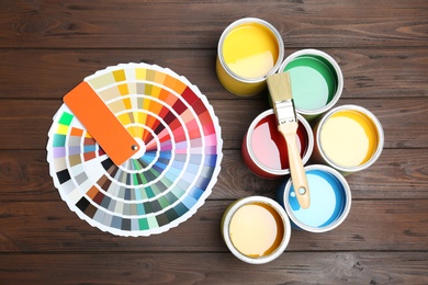 Flat lay composition with paint cans, brush and color palette on wooden background