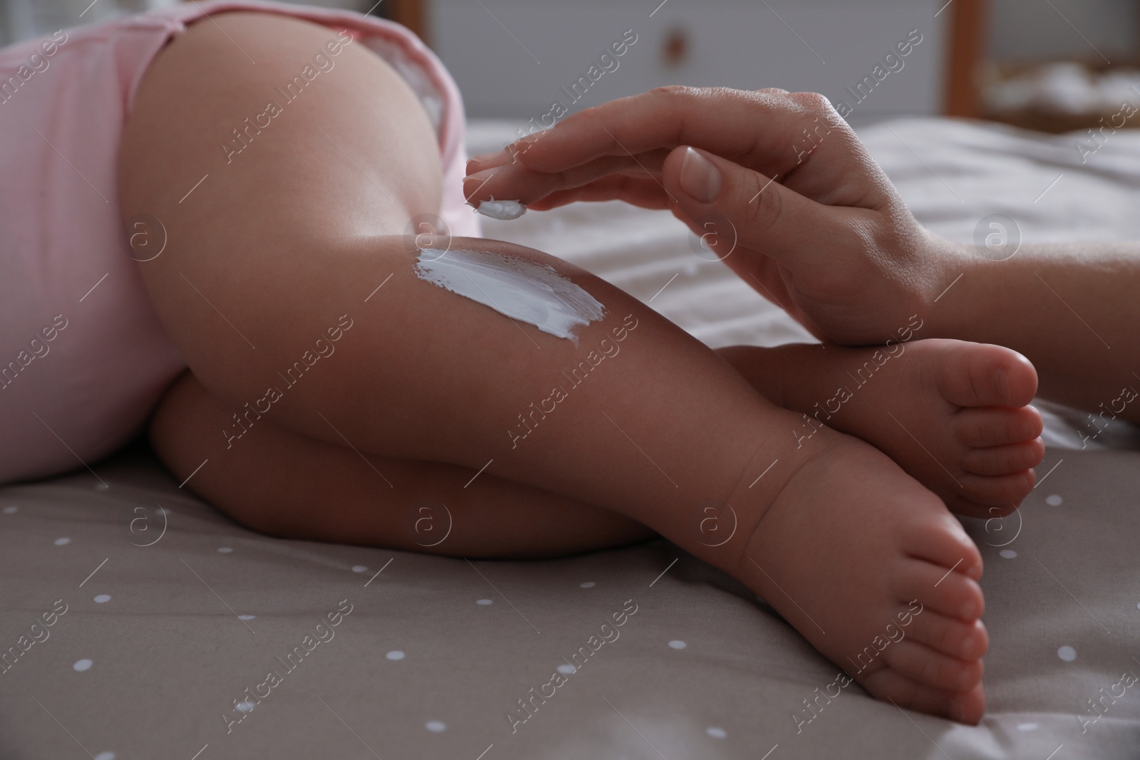 Photo of Mother applying moisturizing cream on her little baby at home, closeup