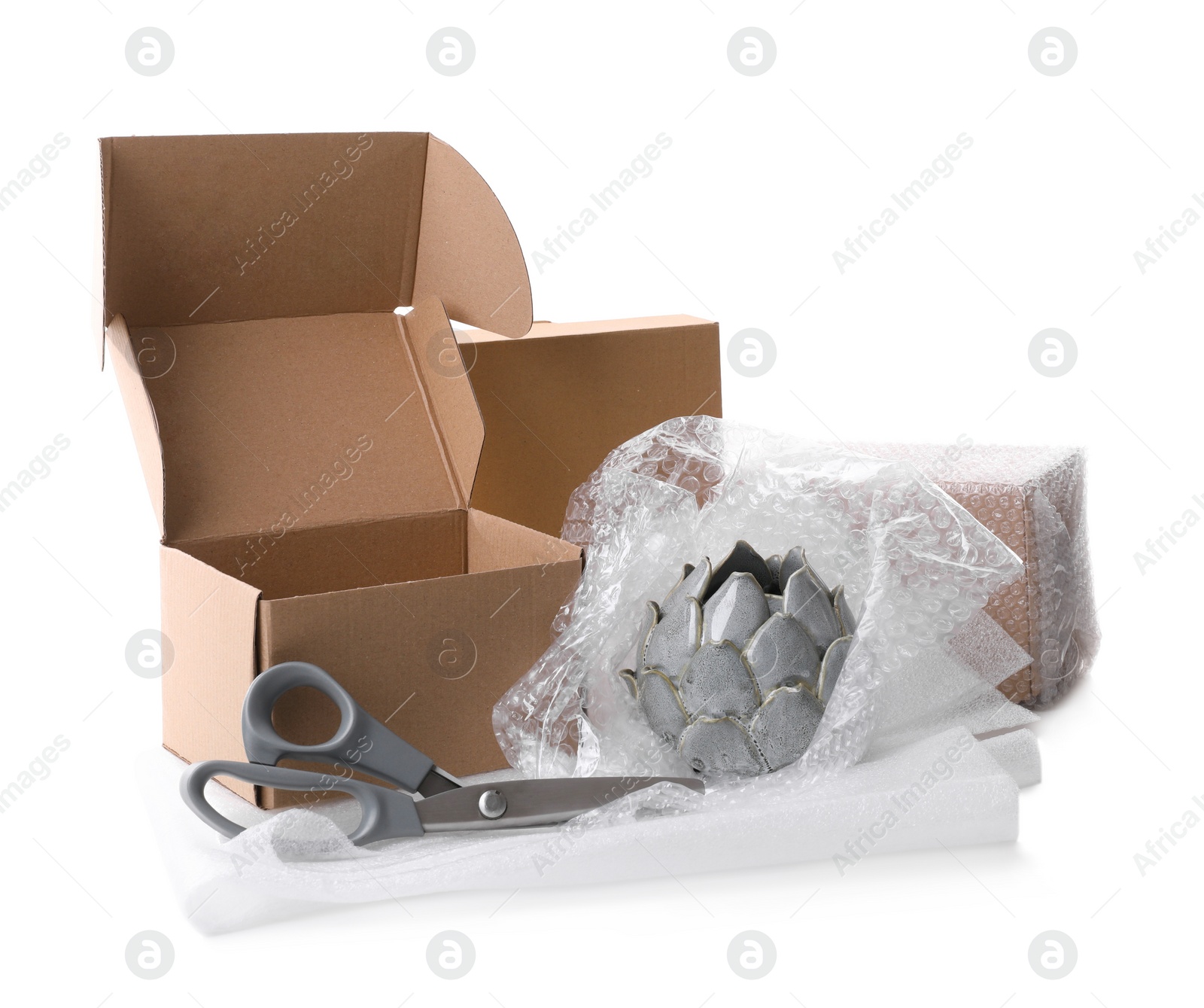 Photo of Cardboard boxes, bubble wrap, scissors and ceramic decor item on white background
