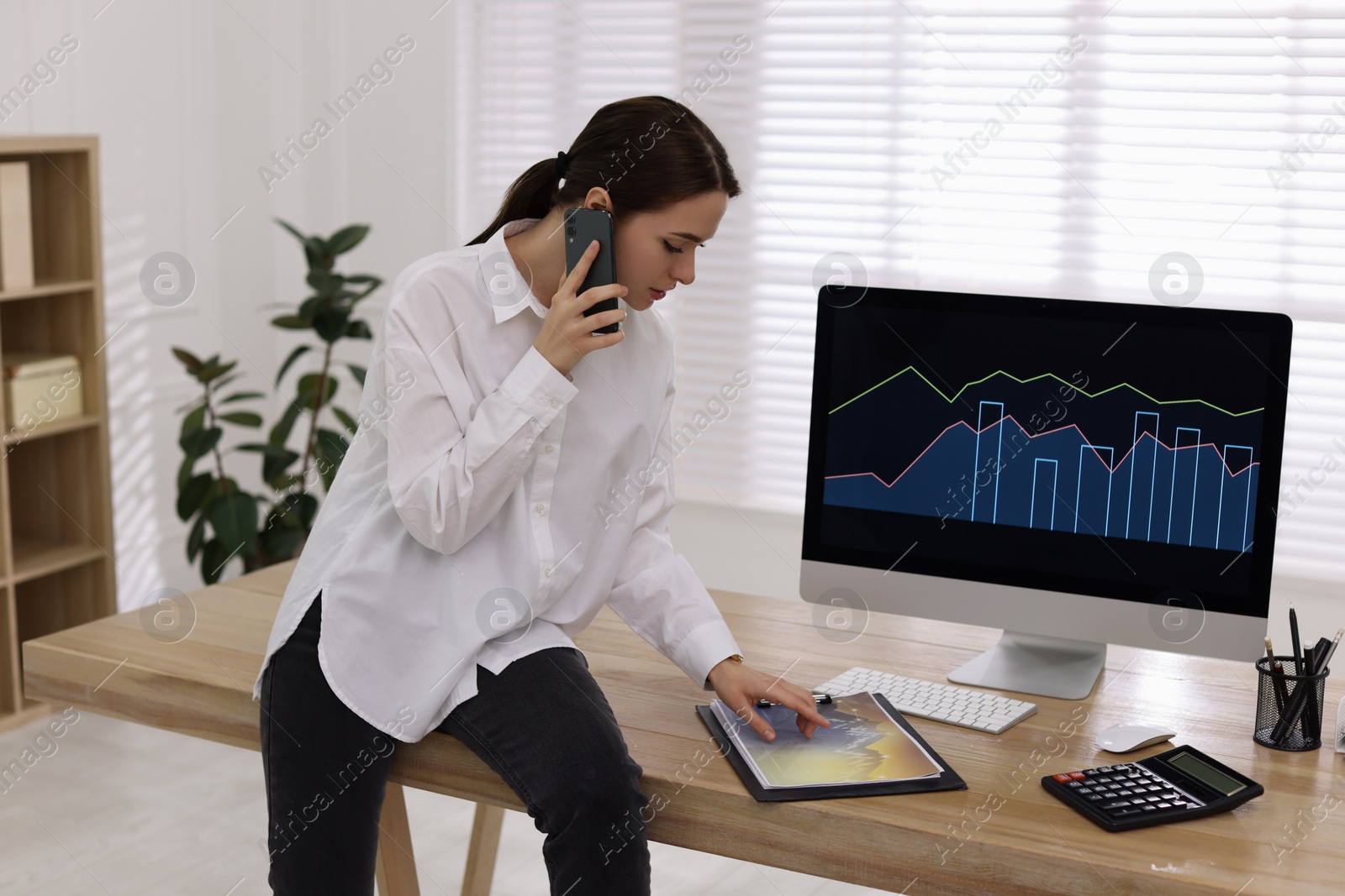 Photo of Businesswoman talking on phone while working in office. Forex trading