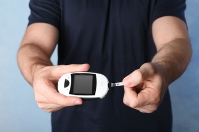 Photo of Man holding glucometer on color background. Diabetes test