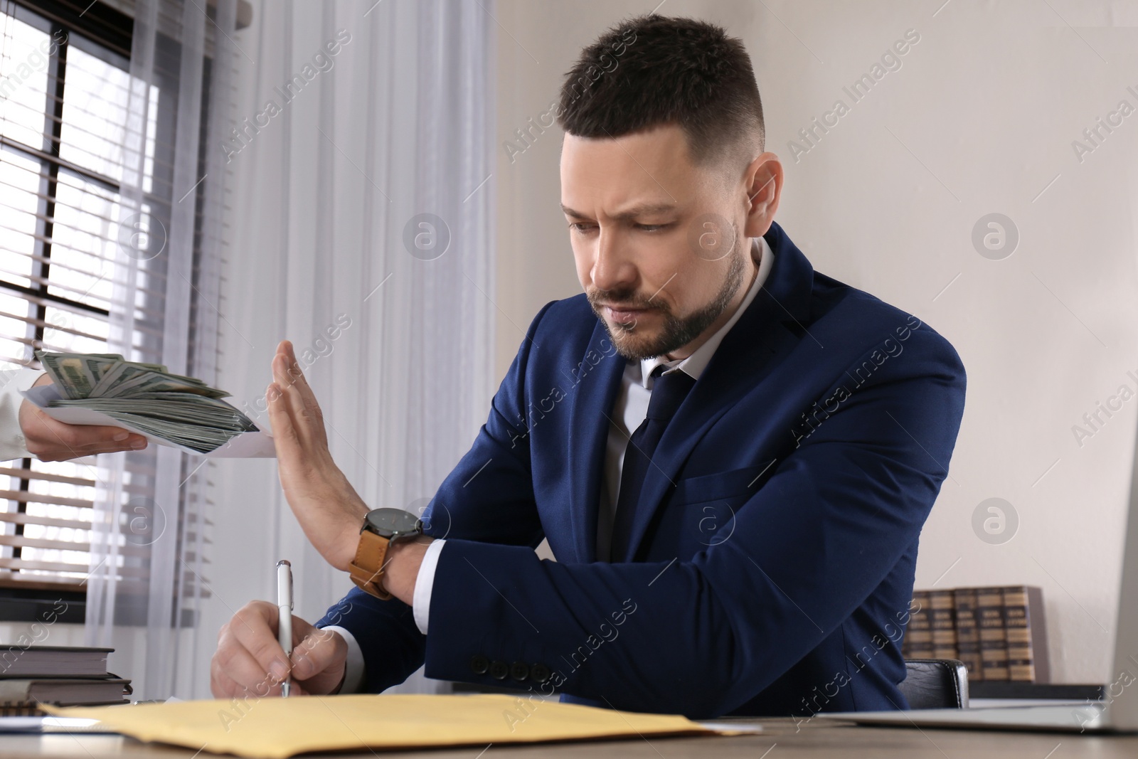 Photo of Businessman rejecting bribe at table in office