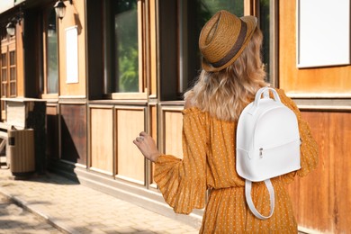 Photo of Young woman with stylish backpack outdoors, back view