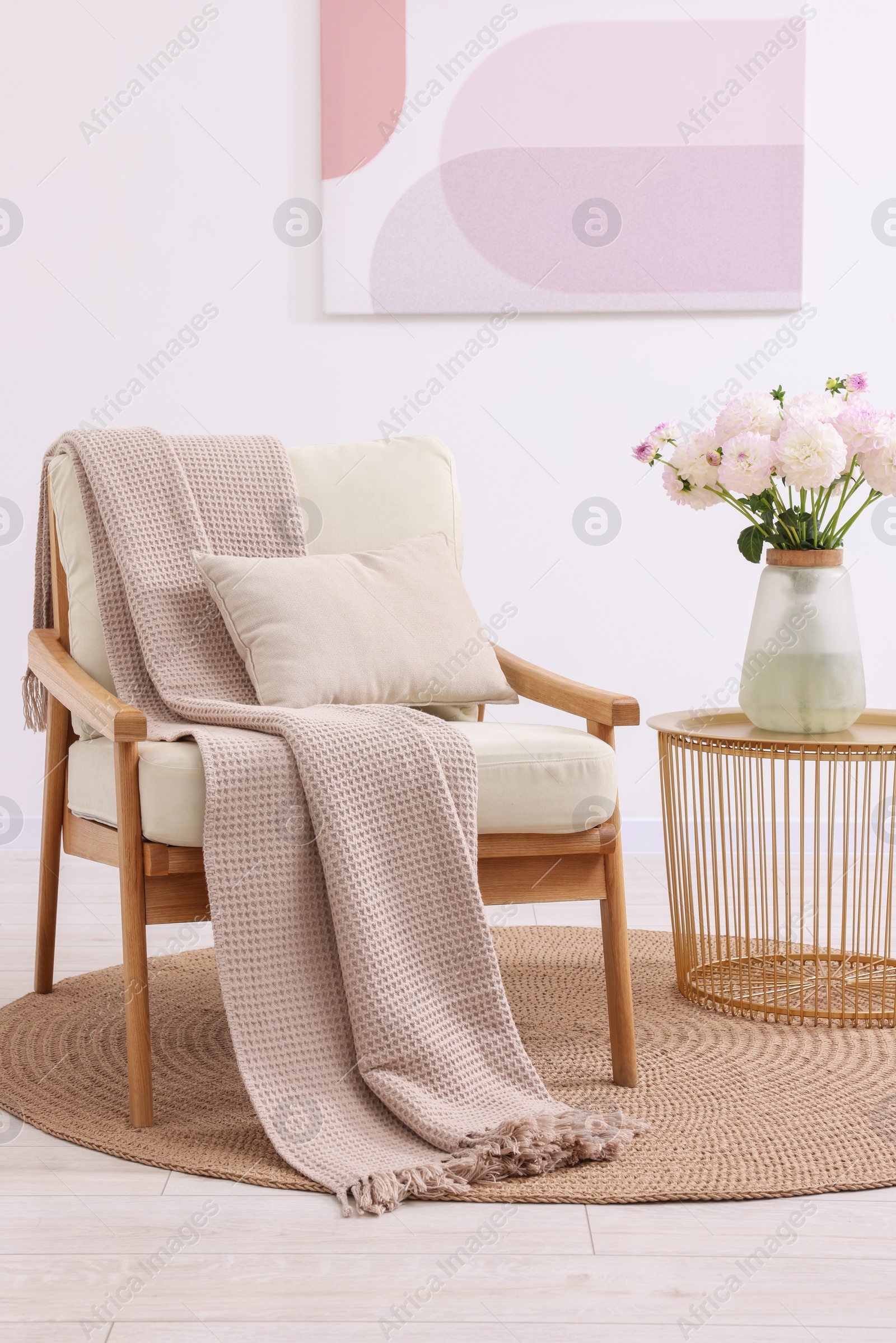 Photo of Comfortable armchair with blanket, pillow, table and beautiful flowers in room