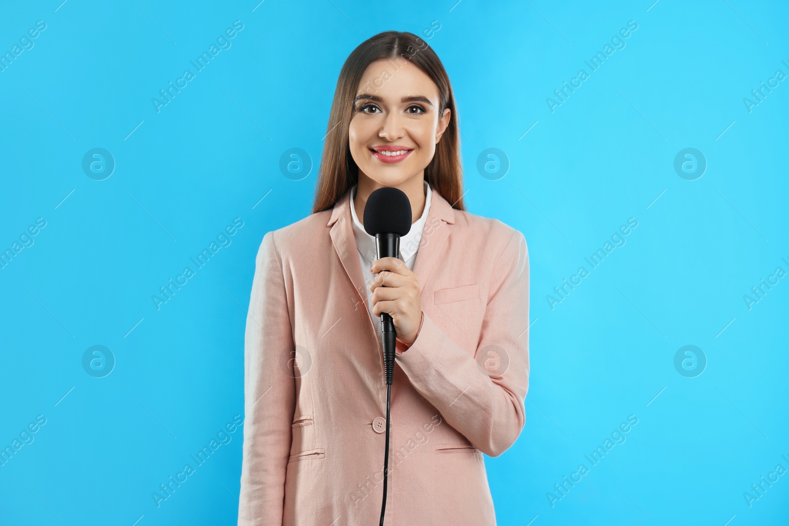 Photo of Young female journalist with microphone on blue background