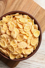 Bowl of tasty corn flakes on wooden table, top view