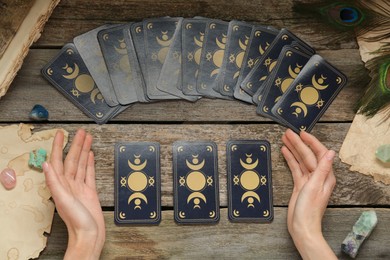 Woman with tarot cards at wooden table, top view. Reverse side