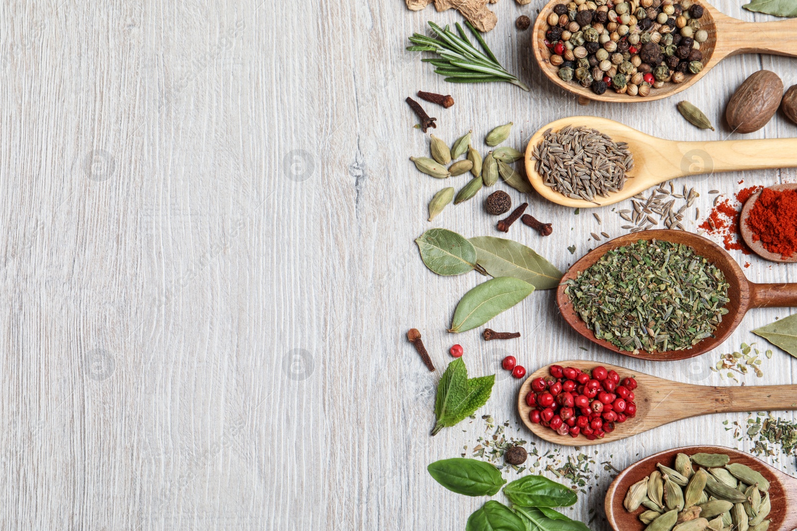 Photo of Different natural spices and herbs on light wooden table, flat lay. Space for text