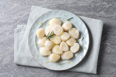 Photo of Raw scallops with lemon zest and rosemary on grey marble table, top view