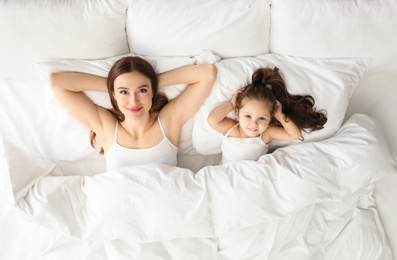 Photo of Mother and little daughter lying in bed, top view