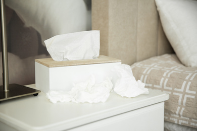 Photo of Used paper tissues and holder on table in bedroom