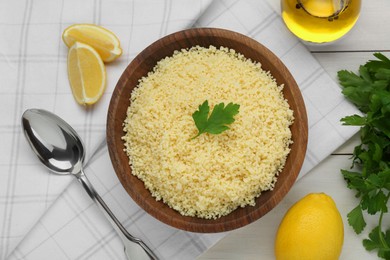 Photo of Tasty couscous and ingredients on white wooden table, flat lay