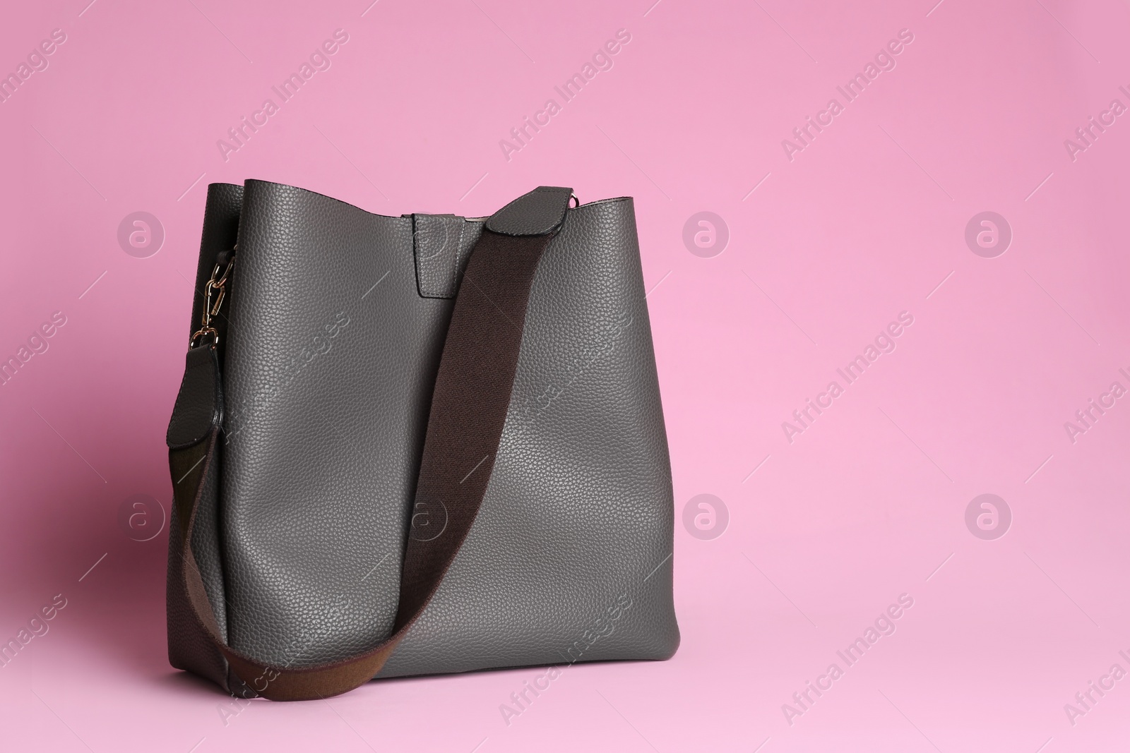 Photo of Stylish woman's bag on light pink background. Space for text