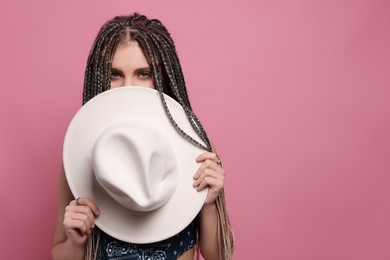 Beautiful woman with long african braids and hat on pink background, space for text