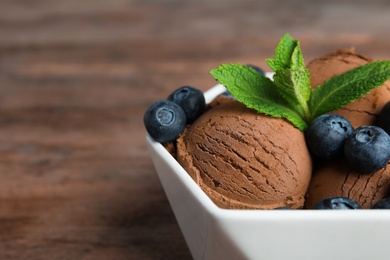 Photo of Bowl of chocolate ice cream and blueberries on wooden table, closeup. Space for text