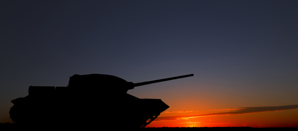 Image of Silhouette of army tank at sunset outdoors. Military machinery