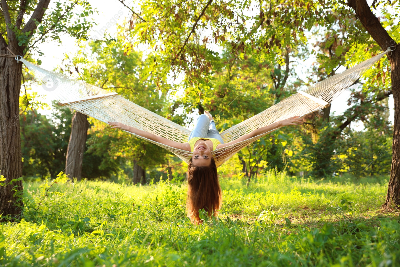 Photo of Young woman resting in comfortable hammock at green garden