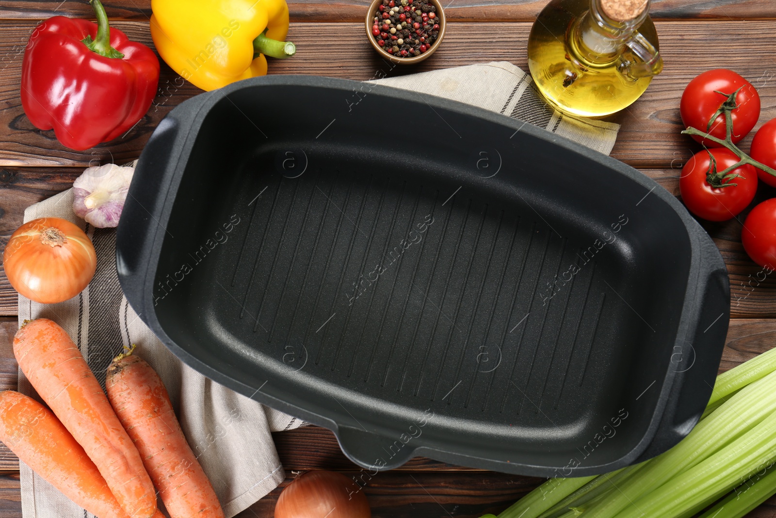 Photo of Black pot with spices and vegetables on wooden table, flat lay