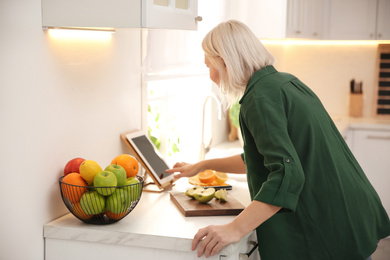 Woman with tablet cooking at counter in kitchen