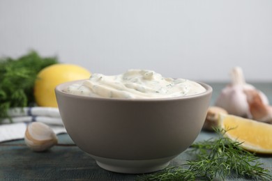 Photo of Tasty creamy dill sauce in bowl on blue wooden table, closeup