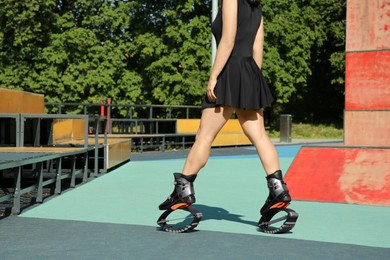 Woman doing exercises in kangoo jumping boots in workout park, closeup