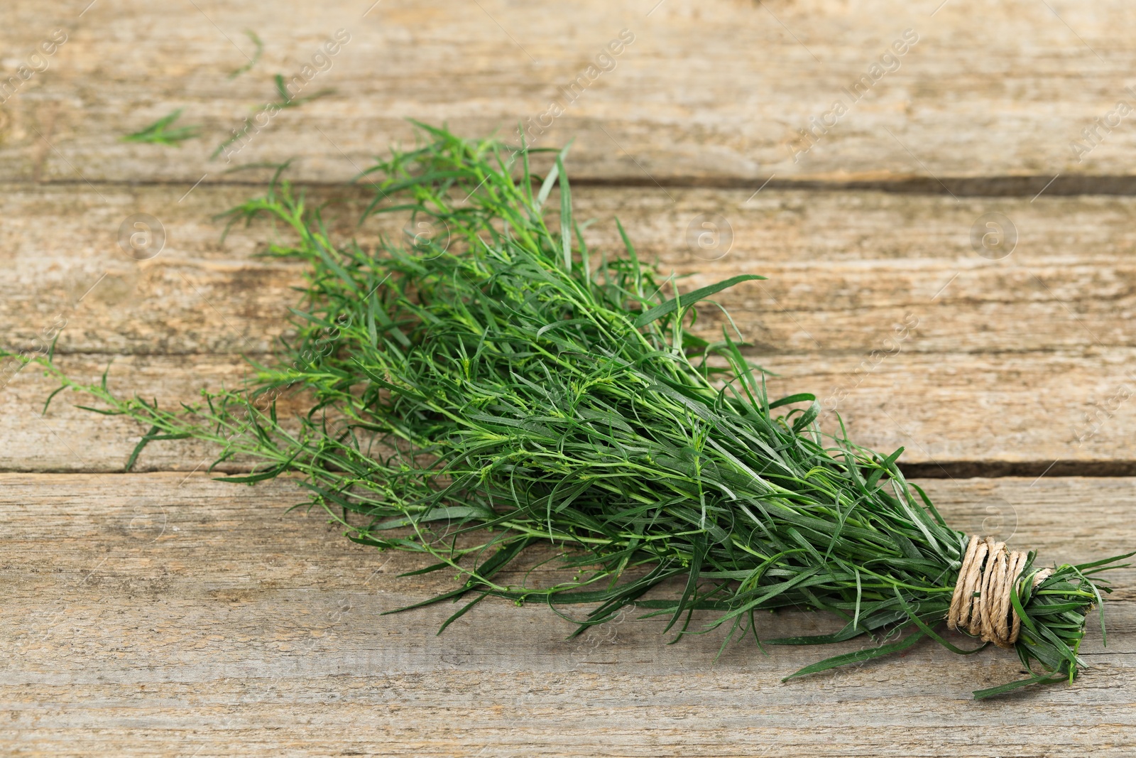 Photo of Bunch of fresh tarragon on wooden table