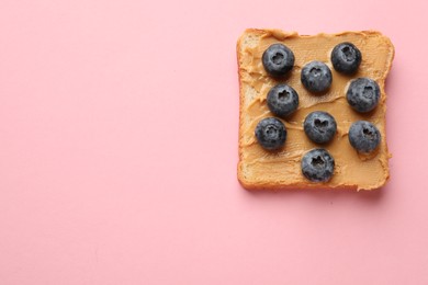 Tasty peanut butter sandwich with fresh blueberries on pink background, top view. Space for text