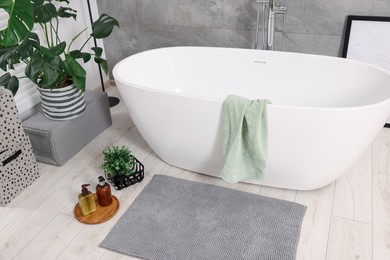 Stylish bathroom interior with soft bath mat and tub