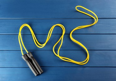 Skipping rope on blue wooden table, top view. Sports equipment