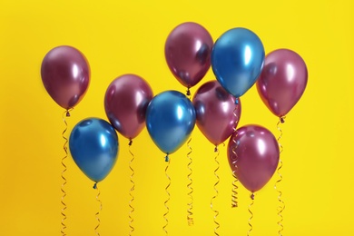 Bright balloons with ribbons on color background