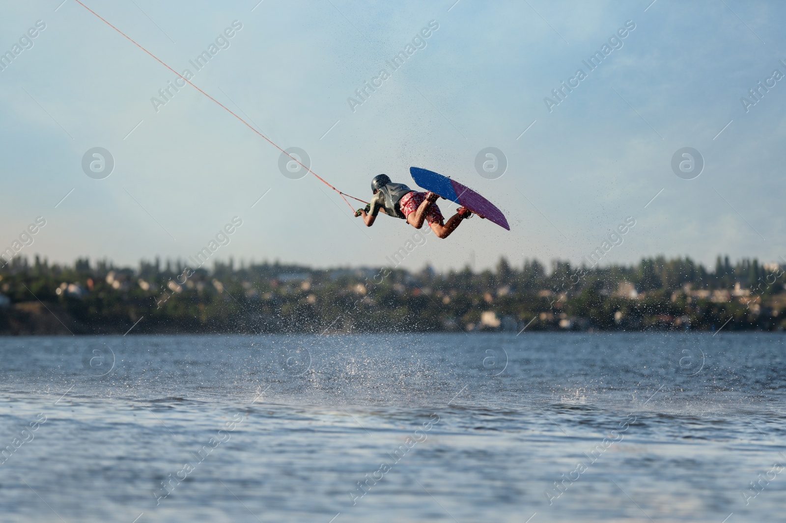 Photo of Teenage wakeboarder doing trick over river. Extreme water sport