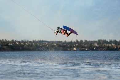 Teenage wakeboarder doing trick over river. Extreme water sport