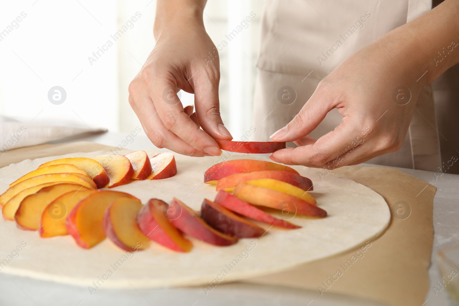 Photo of Woman making peach pie at kitchen table, closeup