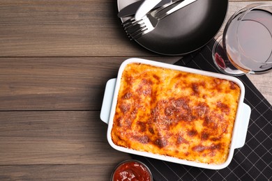 Photo of Tasty cooked lasagna in baking dish on wooden table, flat lay. Space for text