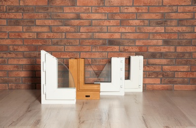 Photo of Samples of modern window profiles on floor against brick wall. Installation service