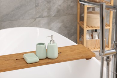 Photo of Set of bath accessories on tub in bathroom