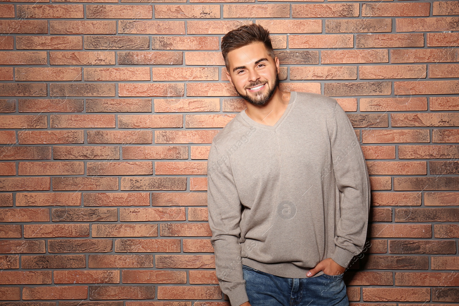 Image of Handsome man wearing warm sweater near brick wall. Space for text