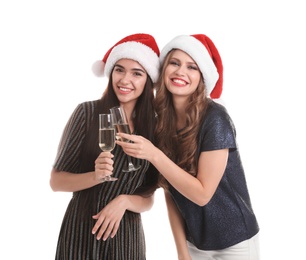 Photo of Beautiful young women in Santa hats with glasses of champagne on white background. Christmas celebration