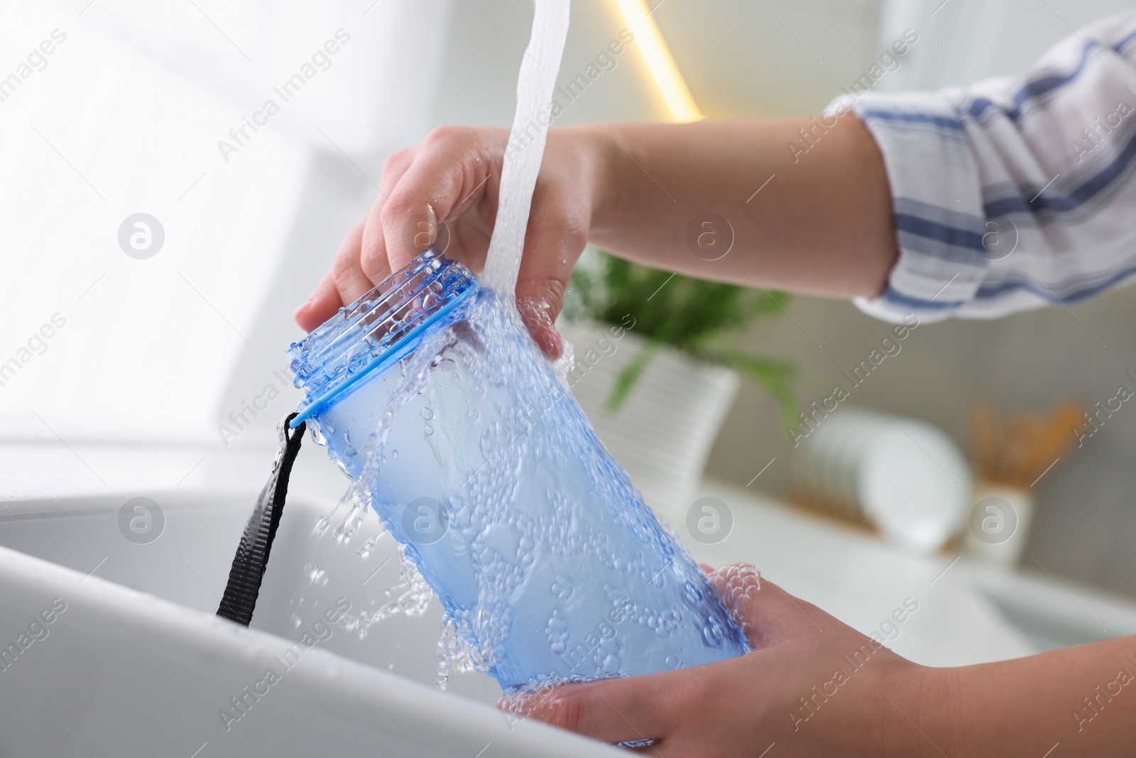 Photo of Woman washing thermo bottle in kitchen, closeup