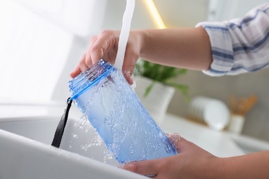 Woman washing thermo bottle in kitchen, closeup