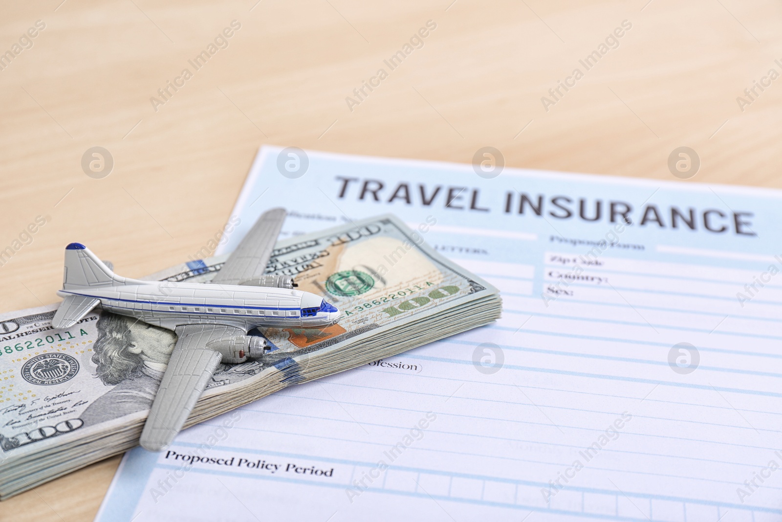 Photo of Composition with toy plane, money and travel insurance form on table