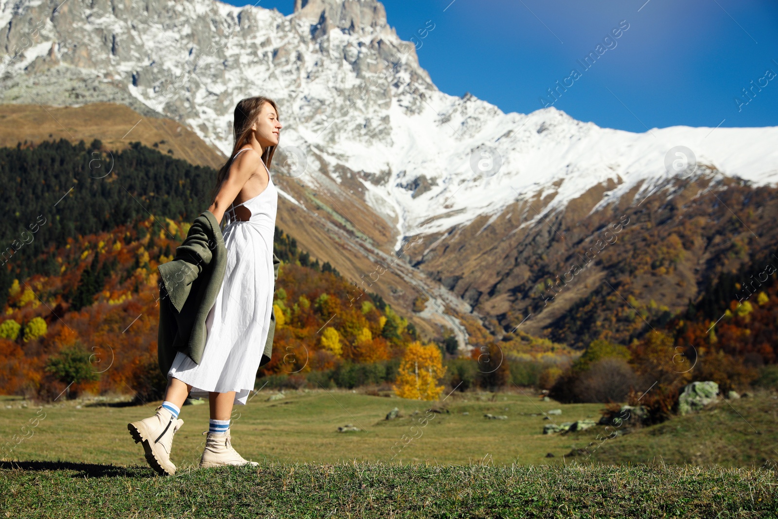 Photo of Young woman walking in beautiful mountains on sunny day. Space for text