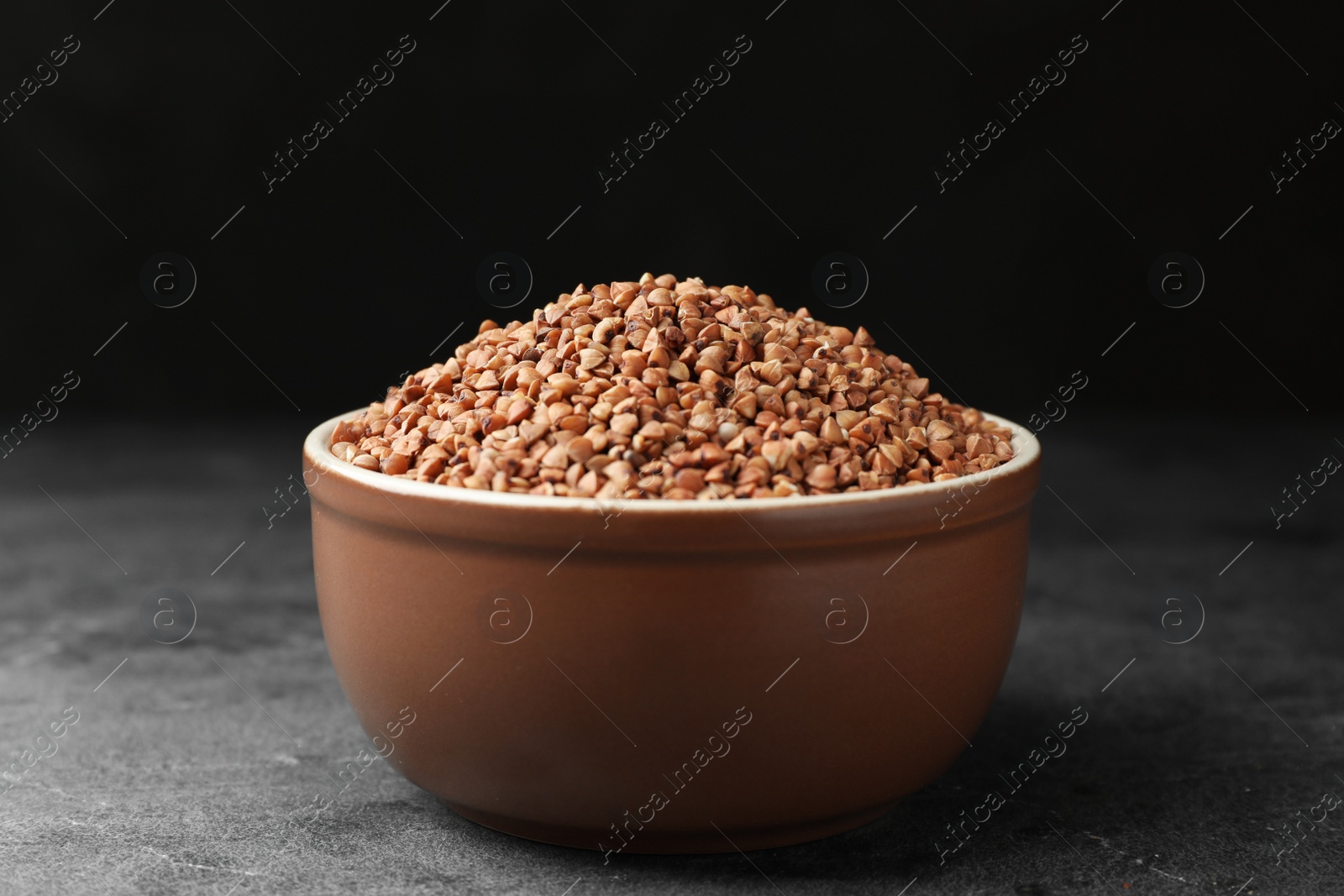 Photo of Buckwheat grains on grey table against black background